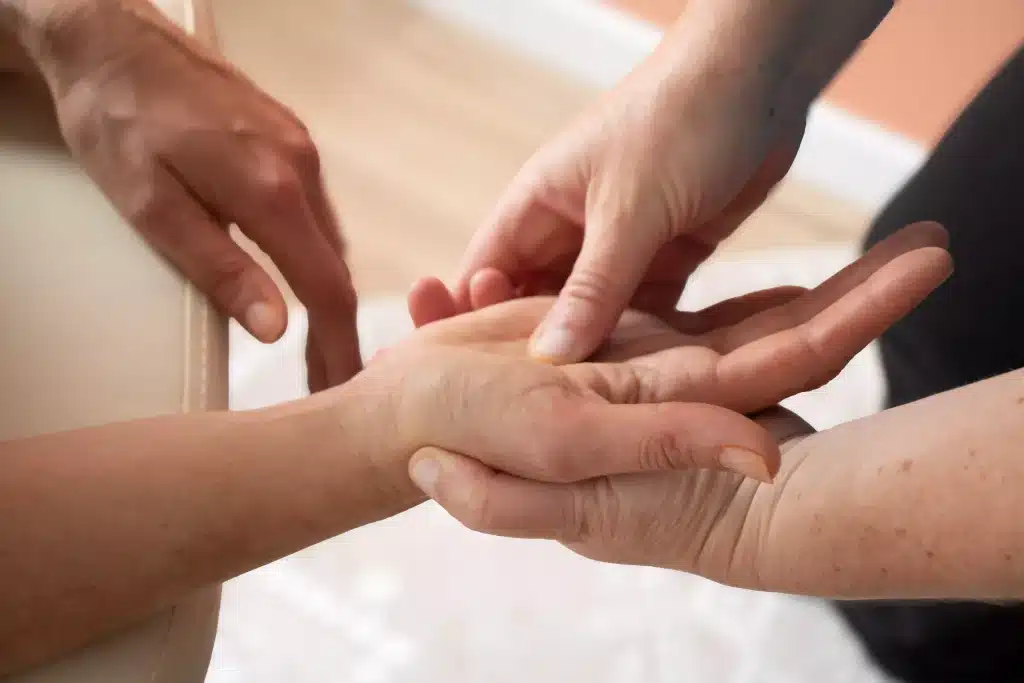 Réflexologue massant la paume de la main d'une cliente lors d'une séance de réflexologie palmaire