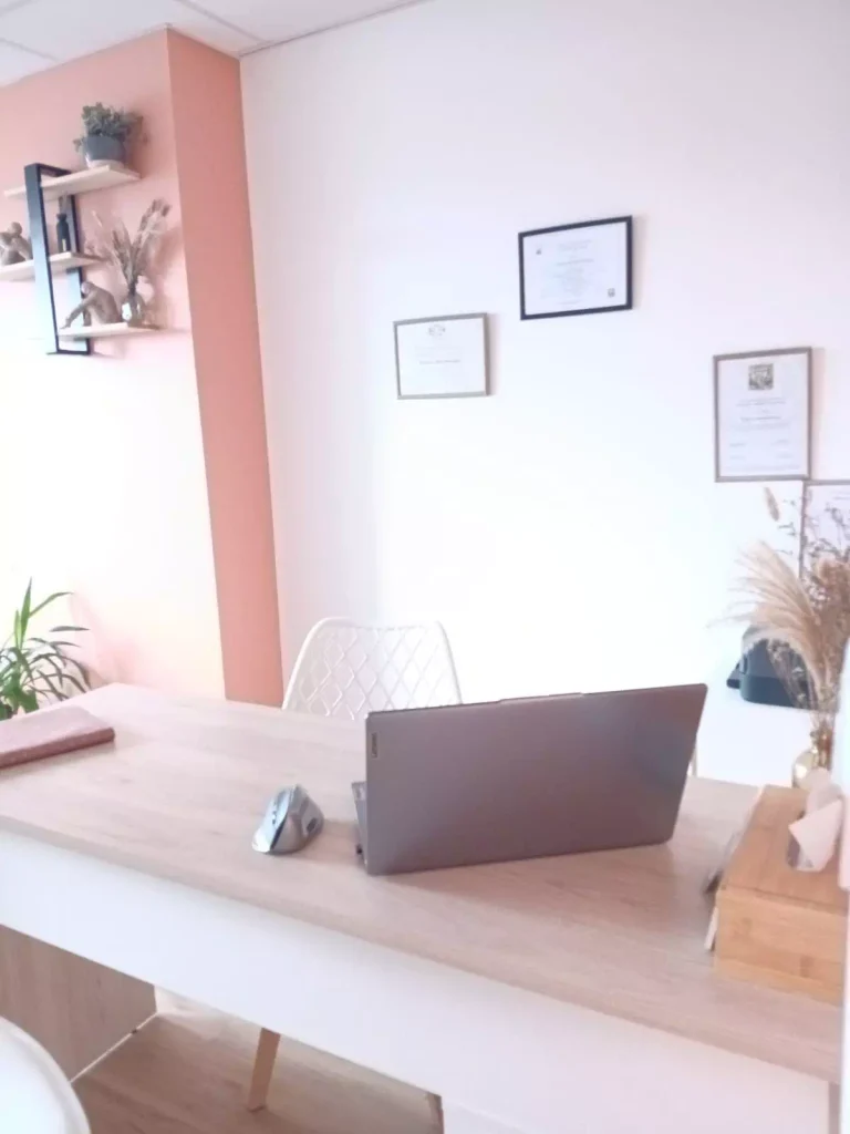 Bureau du cabinet de Virginie Bourdonnais, avec ordinateur portable et plantes, aux murs terracotta